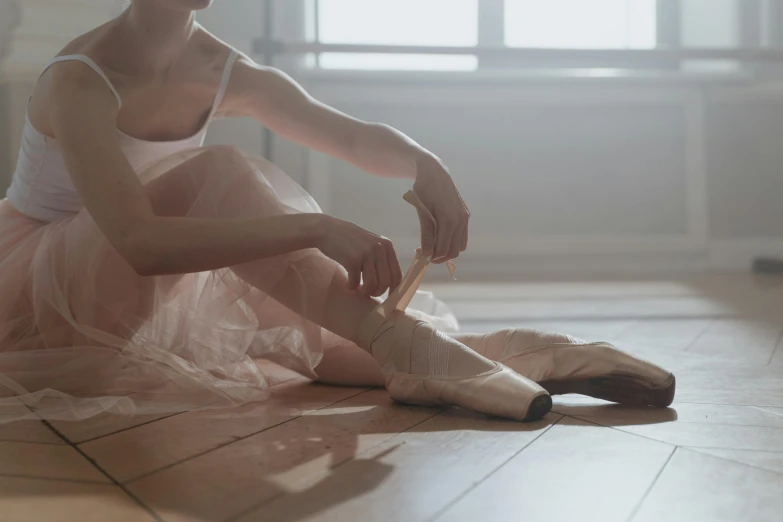 a woman sitting on the floor tying up her ballet shoes, pexels contest winner, arabesque, monia merlo, sydney hanson, bandages, shiny soft skin
