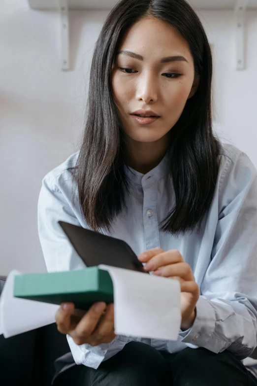 a woman sitting on a couch reading a book, pexels contest winner, asian woman made from origami, holding an ace card, inspect in inventory image, female with long black hair