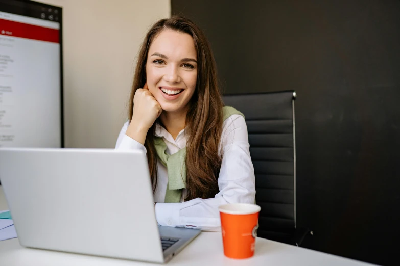 a woman sitting in front of a laptop computer, lachlan bailey, girl with brown hair, professional image, smiling girl