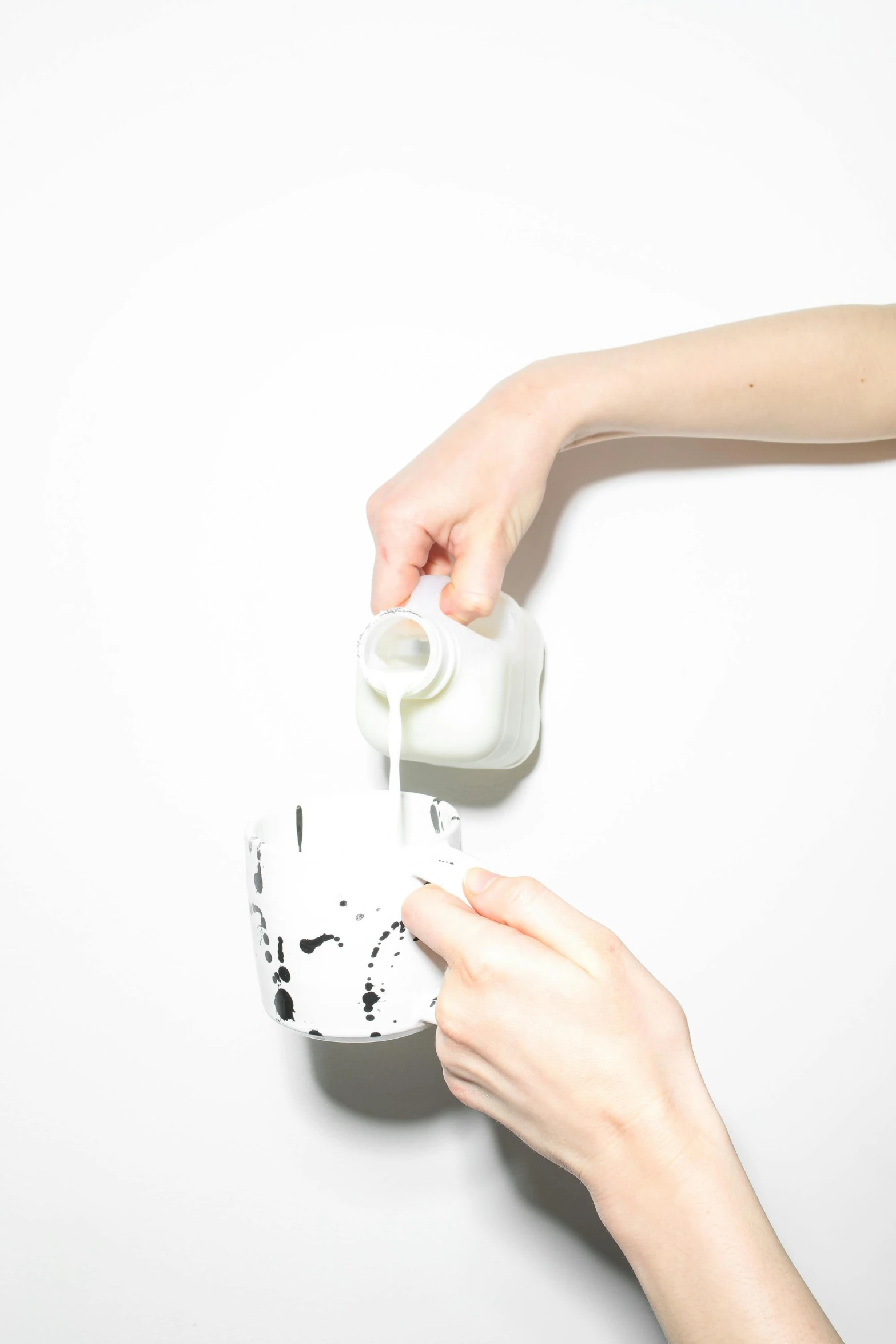 a person pouring milk into a cup, unsplash, process art, on white background, made of plastic, skincare, white with black spots