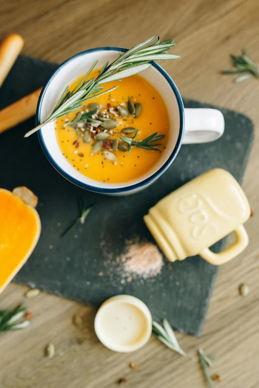 a bowl of soup sitting on top of a cutting board, pexels, dau-al-set, pumpkin, mustard, pastel', square