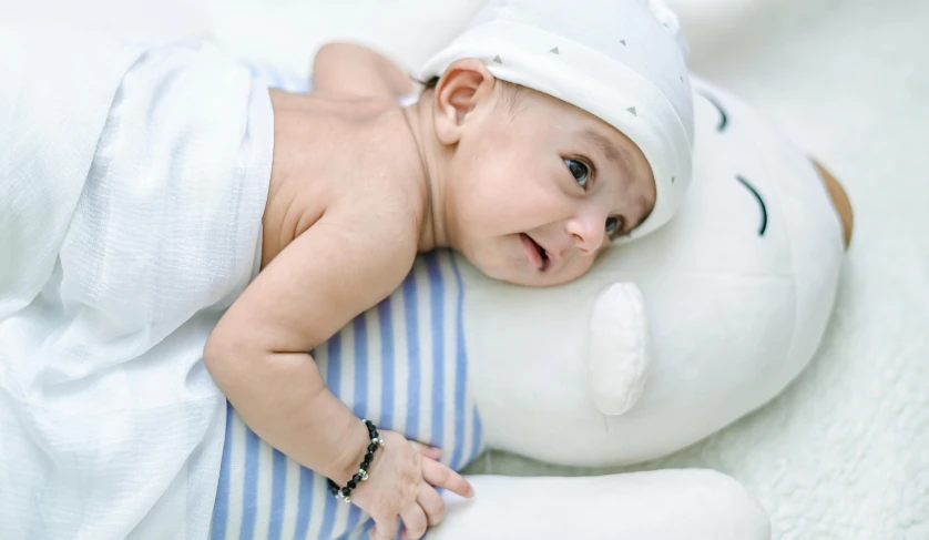 a baby laying on top of a stuffed animal, by Julia Pishtar, wearing a white bathing cap, nivanh chanthara, high quality upload, boy with neutral face