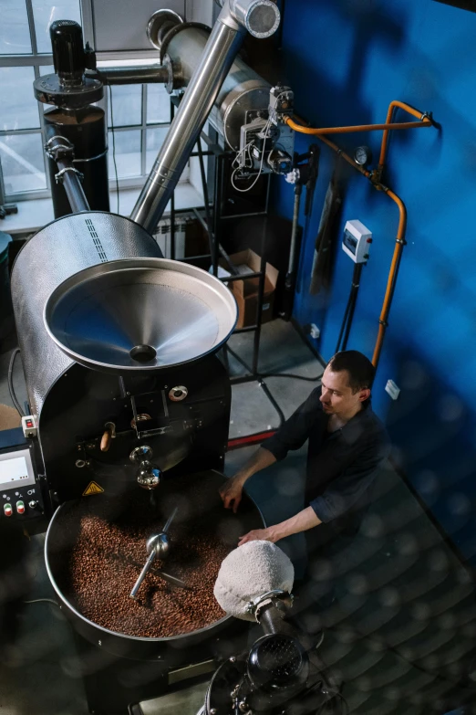 a man standing in front of a machine filled with coffee beans, blue, boiler room, thumbnail, overhead