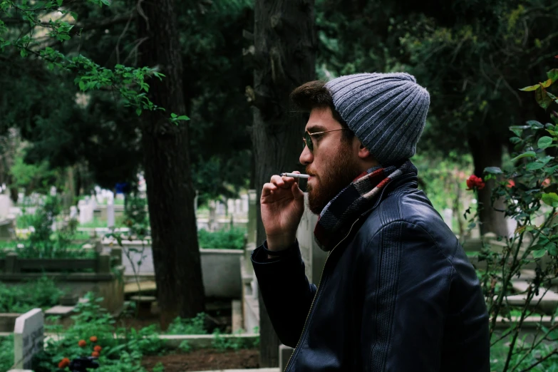 a man standing in a cemetery talking on a cell phone, pexels contest winner, gendo ikari smoking a joint, hipster, eating outside, young greek man