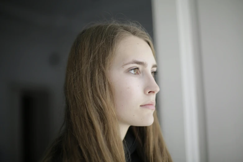 a woman with long hair looking out a window, a character portrait, unsplash, hyperrealism, portrait image, three quarter profile, around 1 9 years old, taken in the late 2010s