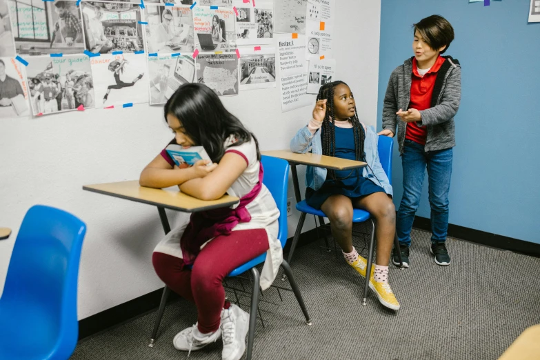 a group of children sitting at desks in a classroom, a portrait, by Matt Cavotta, trending on unsplash, 3 sisters look into the mirror, preparing to fight, full body wide shot, brittney lee