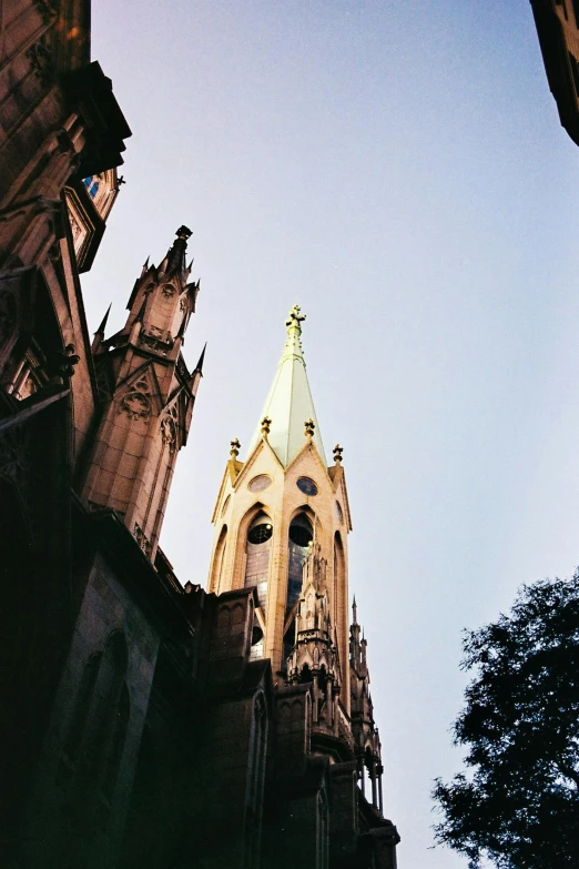 a tall clock tower towering over a city street, by Jacob Burck, unsplash, art nouveau, 1960s color photograph, majestic spires, bottom view, in savannah