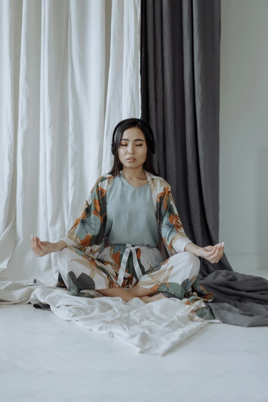 a woman sitting on a bed in a room, inspired by Li Di, unsplash, visual art, meditating pose, wearing a track suit, sufism, vietnamese woman