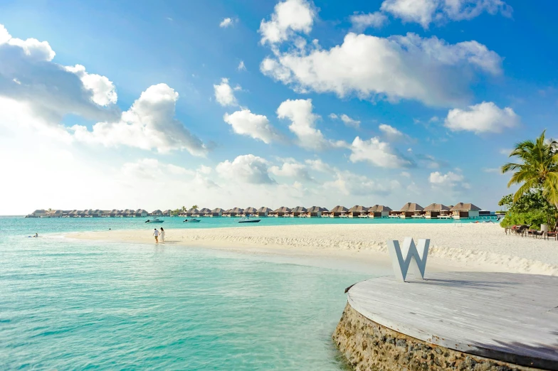 a wooden bench sitting on top of a beach next to the ocean, the letter w, maldives in background, slide show, ameera al-taweel