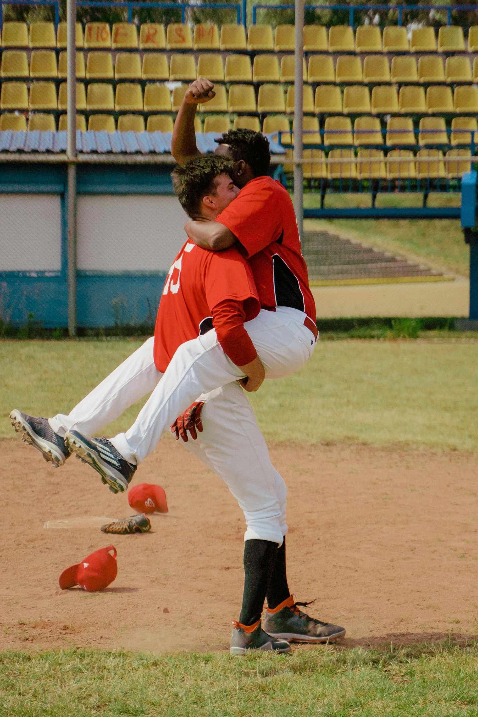 a couple of men standing on top of a baseball field, by Dietmar Damerau, flickr, happening, hugs, doing a kick, tournament, wearing a red backwards cap