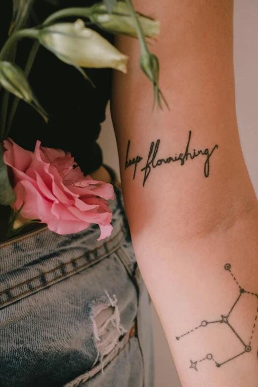 a close up of a person's arm with a tattoo on it, a tattoo, trending on unsplash, happening, flowing lettering, blooming, hand on hips, sitting