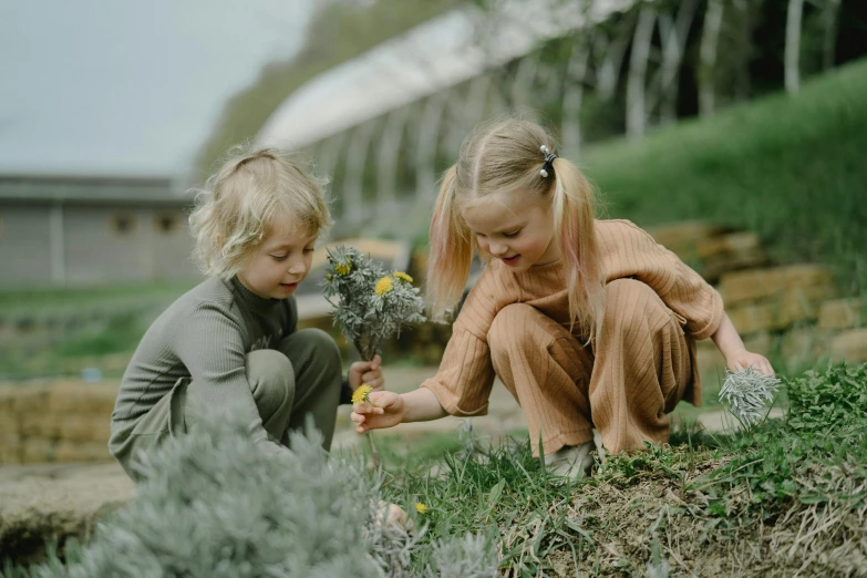 two little girls playing with a bunch of flowers, inspired by Elsa Beskow, pexels contest winner, permaculture, grey, boy and girl, thumbnail