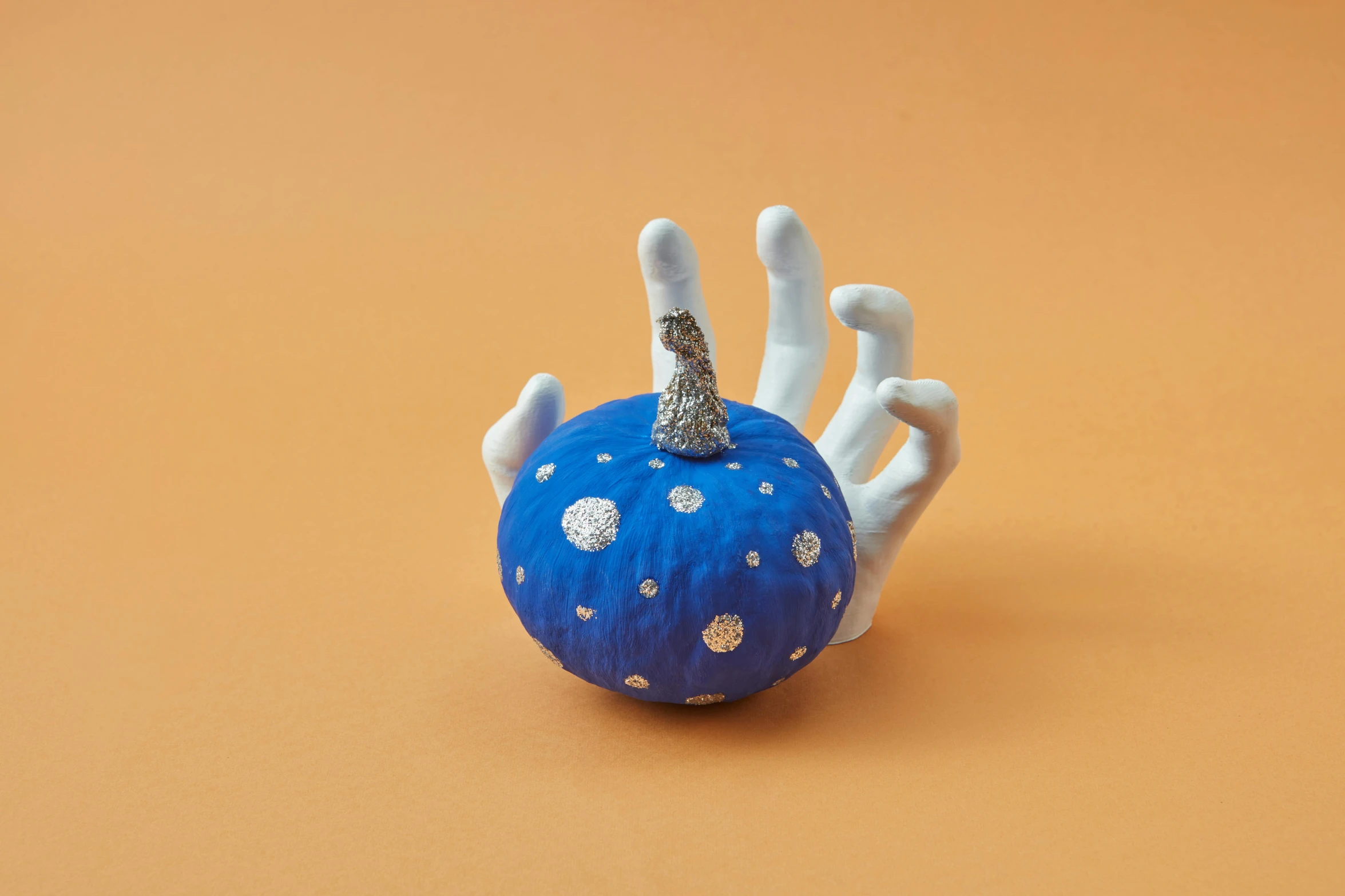 a blue pumpkin sitting on top of a table, a surrealist sculpture, inspired by Yayou Kusama, stylised hand painted textures, blue and silver, tissue ornament, miniature product photo