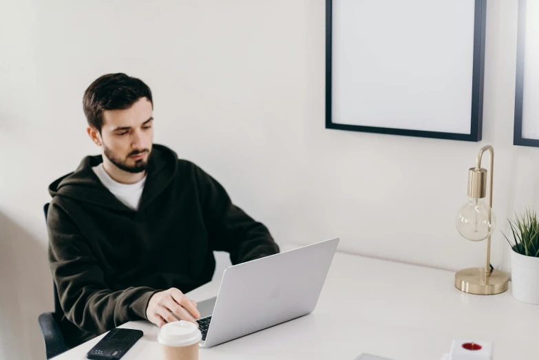 a man sitting at a table working on a laptop, by Carey Morris, trending on unsplash, in a white room, avatar image, background image, lachlan bailey