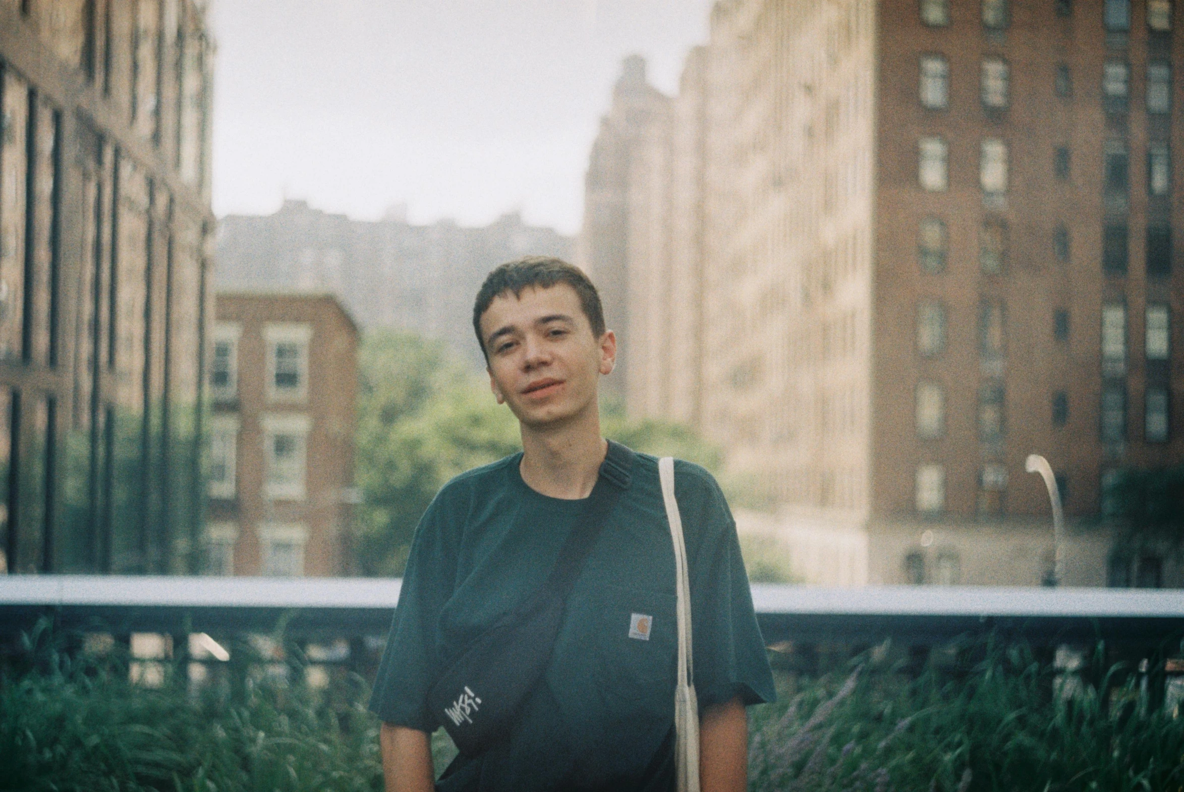 a man standing in front of tall buildings, an album cover, unsplash, realism, portrait of 1 5 - year - old boy, rex orange county, halfbody headshot, taken on a 2000s camera