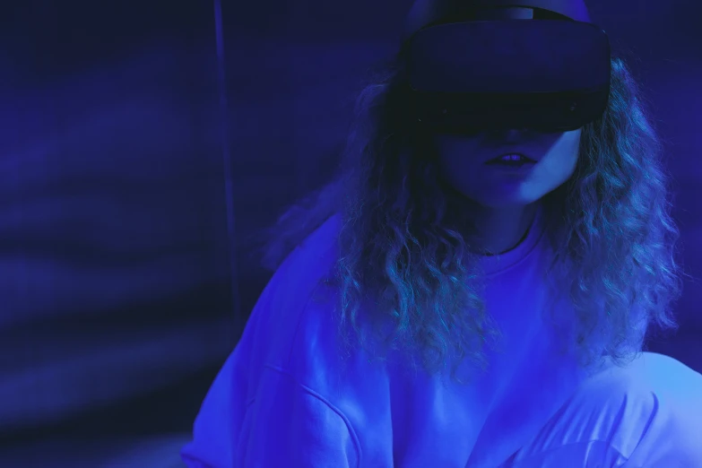 a woman wearing a virtual reality headset, a hologram, trending on pexels, moody blue lighting, blue clothing, promo image, cyberpunk teenager bedroom