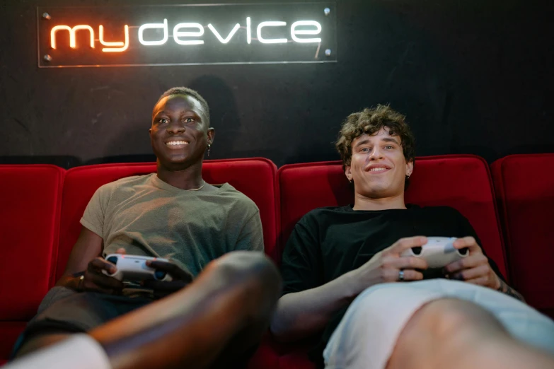 a couple of men sitting on top of a red couch, pexels, gameboy, adut akech, server in the middle, hey buddy