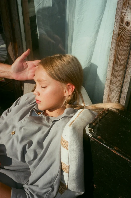 a little girl sitting on top of a wooden bench, movie still of a tired, overhead sun, julia hetta, hand on cheek