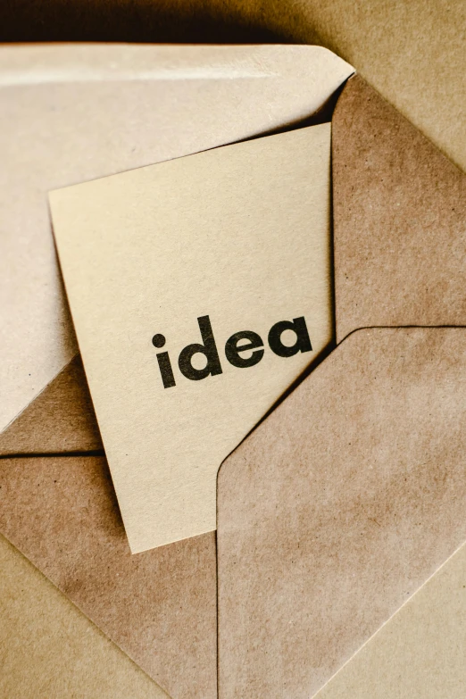 an open envelope with a piece of paper with the word idea written on it, inspired by Géza Dósa, light brown colors, thumbnail, sustainable materials, patent