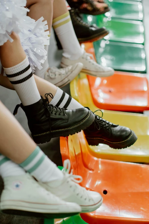 a group of people sitting next to each other on a bench, by Elsa Bleda, trending on pexels, aestheticism, striped socks, in a school classroom, mall goth, roller skating