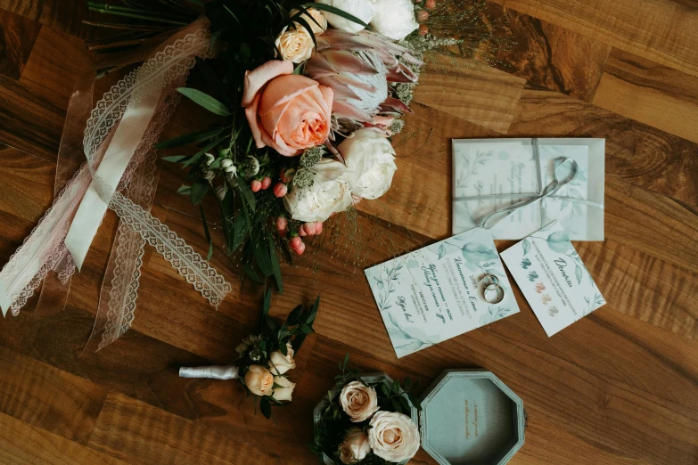 a bouquet of flowers sitting on top of a wooden floor, pexels contest winner, pair of keycards on table, peach embellishment, various items, high details photo