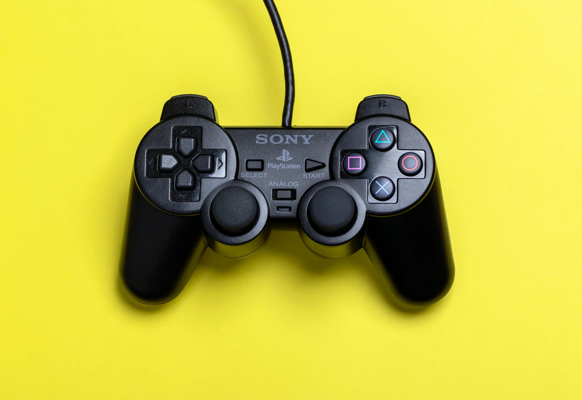 a close up of a game controller on a yellow surface, by Carey Morris, pexels, square enix, playstation 2, black, taken in the mid 2000s