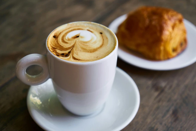 a cup of coffee and a croissant on a table, trending on unsplash, square, fan favorite, latte art, white