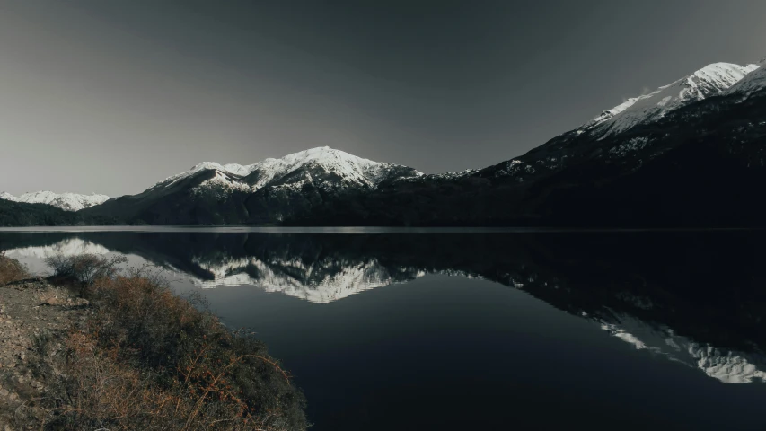 a large body of water with mountains in the background, pexels contest winner, minimalism, mirrored, dark and white, 8 k cinematic, winter lake setting