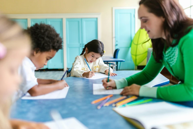 a woman sitting at a table with a group of children, a child's drawing, by Arabella Rankin, pexels contest winner, studying in a brightly lit room, photo of a classroom, bending down slightly, tiffany dover