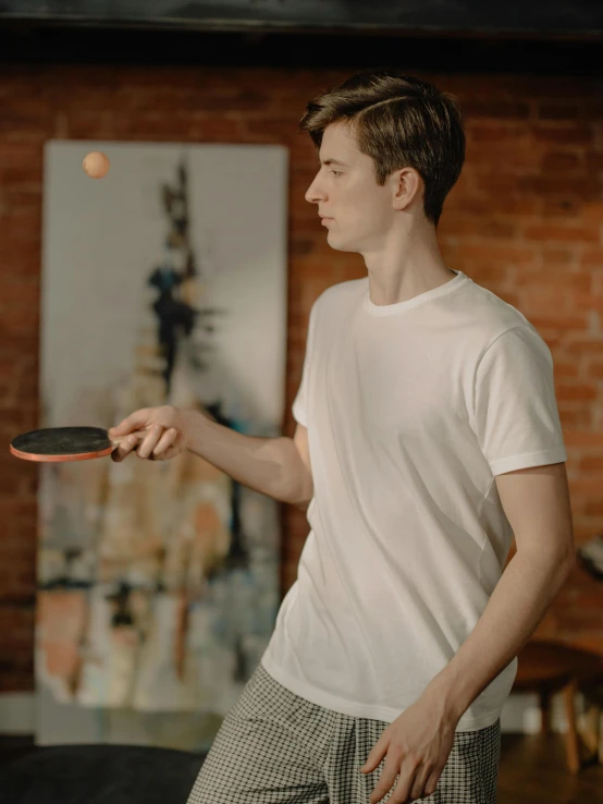a man standing in front of a brick wall holding a ping pong paddle, pexels contest winner, renaissance, wearing a light shirt, playing, at home, gif