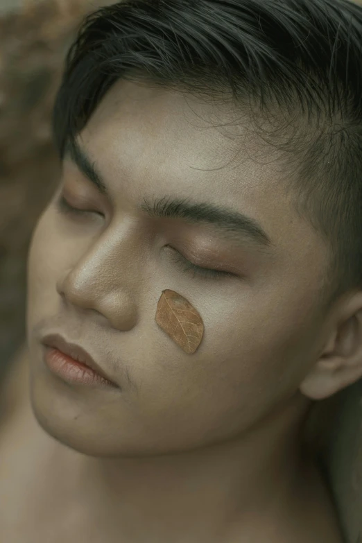 a man with a lot of makeup on his face, inspired by Dai Jin, trending on pexels, conceptual art, chilling on a leaf, movie frame still, cinnamon skin color, beautiful boy