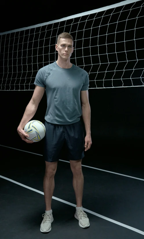 a man standing in front of a volleyball net holding a ball, inspired by Ruud Janssen, dribble, wearing shorts and t shirt, promotional image, tall shot, portrait of benedict cumberbatch