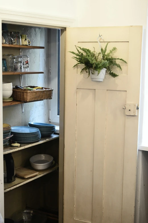a pantry with a door open next to a window, inspired by Harriet Backer, featured on pinterest, wreath of ferns, hand built ceramics, photo taken in 2018, an escape room in a small
