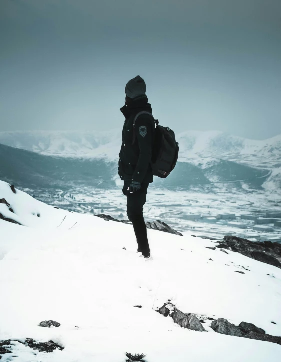 a person standing on top of a snow covered mountain, wearing a black jacket, with a backpack, trending on vsco, multiple stories