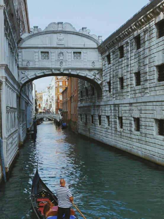 a gondola going under a bridge in venice, a photorealistic painting, pexels contest winner, renaissance, over the shoulder, today\'s featured photograph 4k, massive arch, 2022 photograph