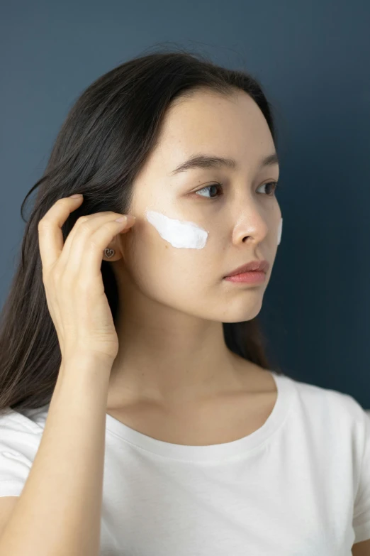 a woman putting cream on her face, trending on pexels, detailed face of a asian girl, profile posing, square, silicone skin