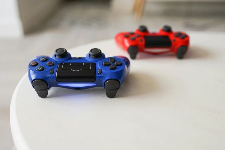 a couple of video game controllers sitting on top of a table, red blue, taken with sony alpha 9, indoor shot, uploaded