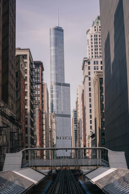 a train traveling through a city next to tall buildings, trump tower, low quality photo, fan favorite, glass and steel