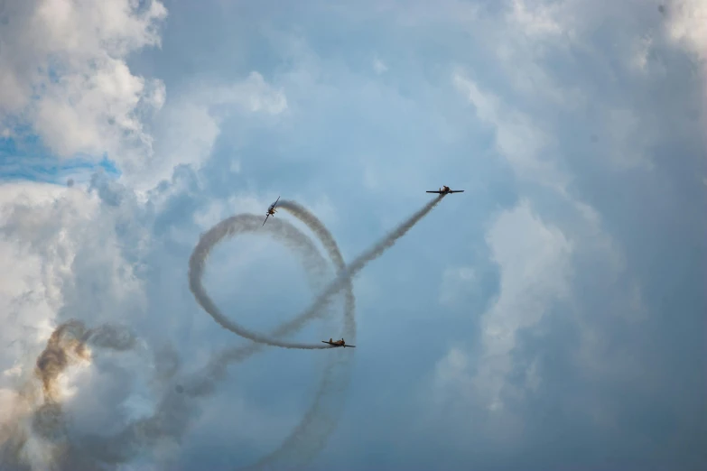 a couple of airplanes flying through a cloudy sky, pexels contest winner, precisionism, spiral smoke, festivals, slide show, circle pit