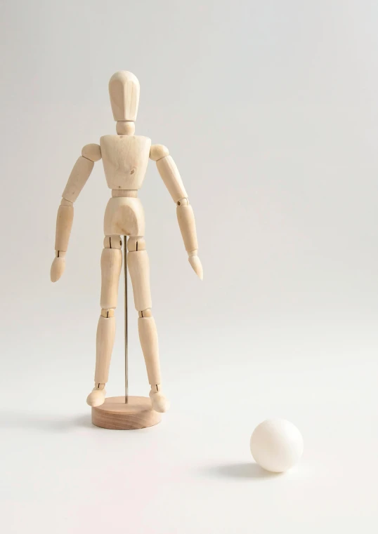 a wooden mannequin standing next to a white ball, kinetic art, detailed product image, hero action pose, art set, medium-shot