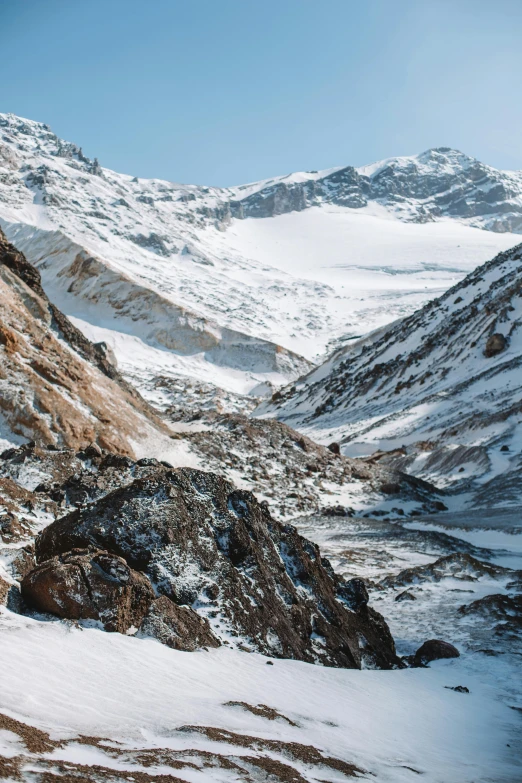 a man riding a snowboard down a snow covered slope, an album cover, trending on unsplash, les nabis, geological strata, nepal, dry river bed, distant valley