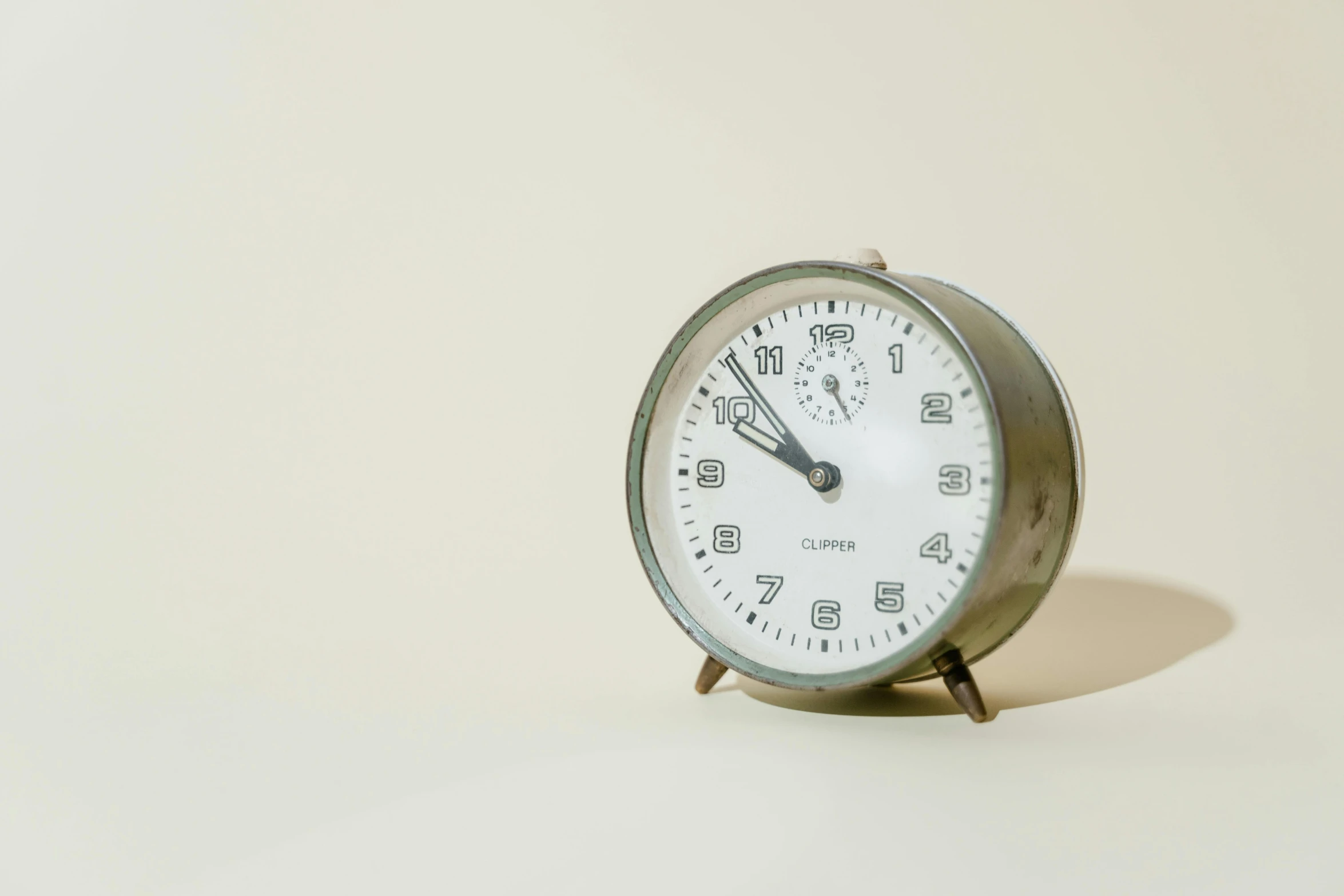 a small clock sitting on top of a table, trending on unsplash, bauhaus, silver，ivory, plain background, getty images, gray