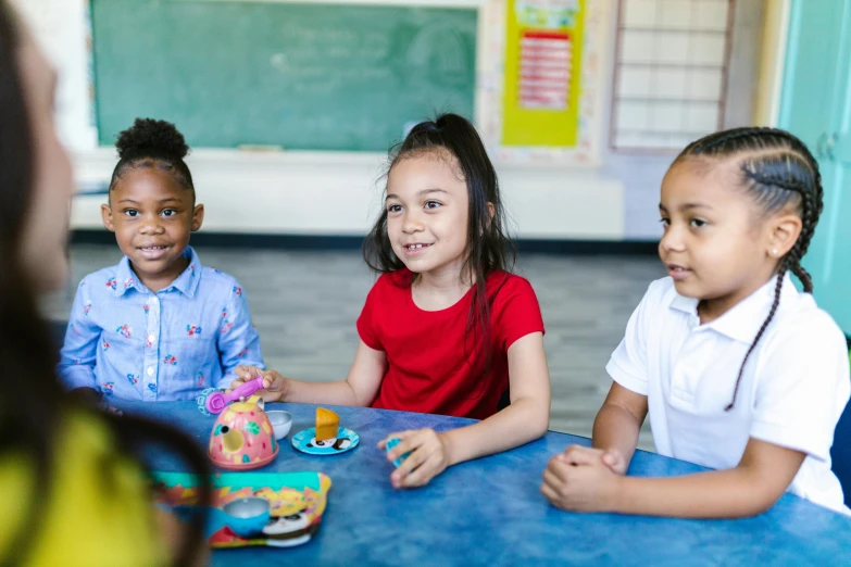 a group of children sitting around a blue table