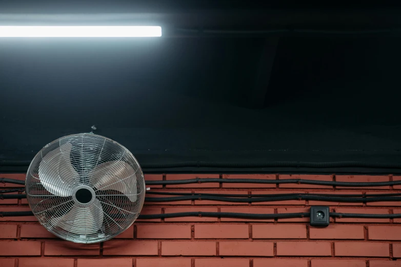 a fan sitting on top of a brick wall, pexels contest winner, fluorescent lights from ceiling, refrigerated storage facility, blades in the dark, outdoors at night