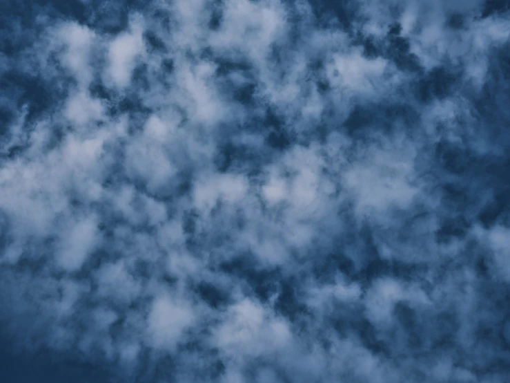 a plane flying through a cloudy blue sky, an album cover, pexels, surrealism, blue fur with white spots, background ( dark _ smokiness ), cloudy night, layered stratocumulus clouds