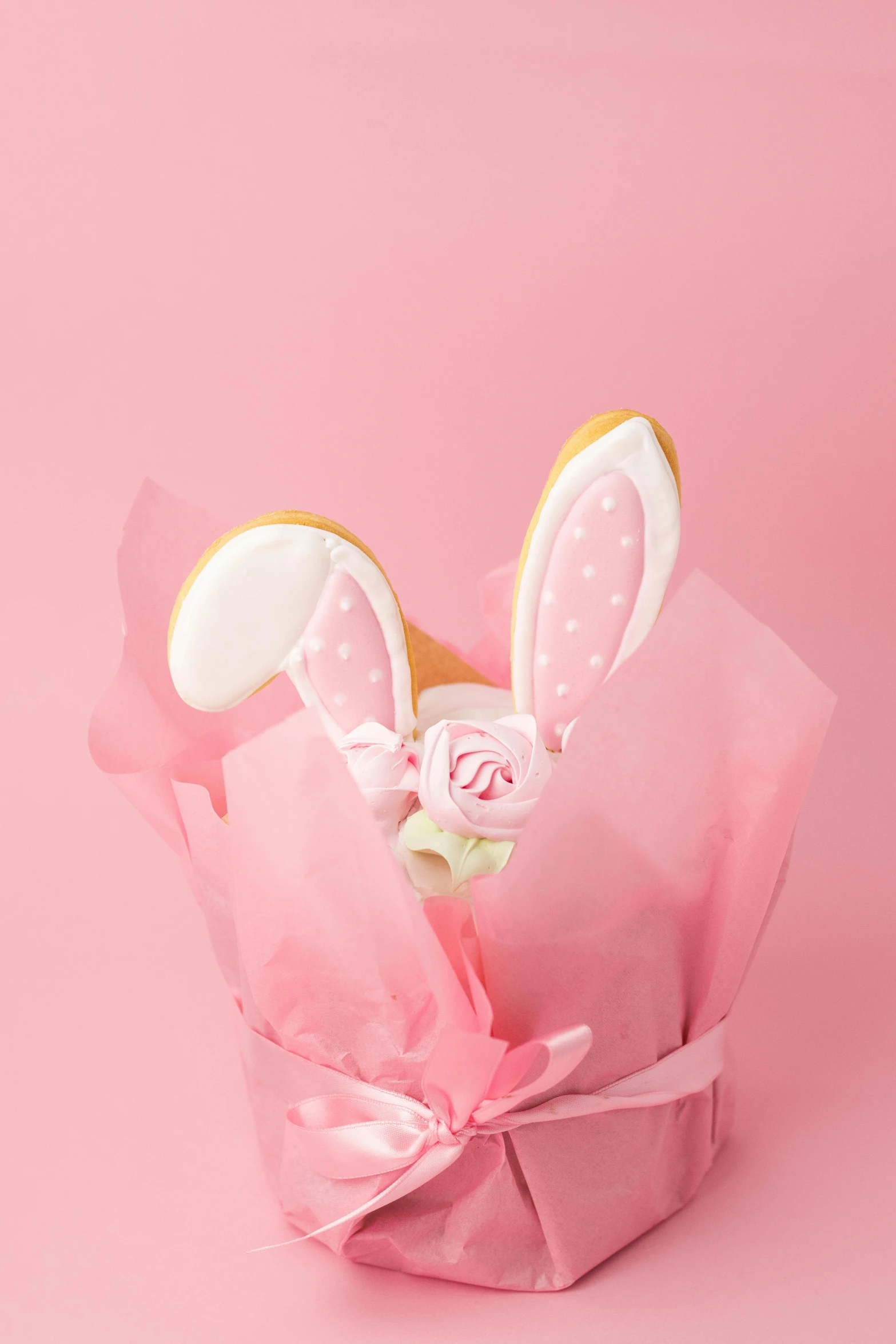 a cookie in a pink wrapper on a pink background, with bunny ears, detailed product image, pink rose, detail shot