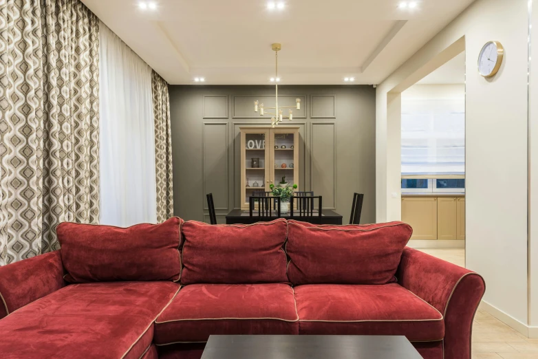 a red couch sitting in a living room next to a table, by Adam Marczyński, pexels contest winner, beige color scheme, open plan, indoor lighting, gold and luxury materials