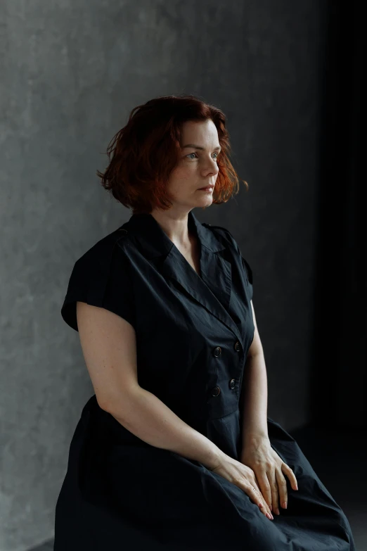 a woman in a black dress sitting on a chair, a portrait, inspired by Anna Füssli, unsplash, a redheaded young woman, non-binary, thoughtful ), a portrait of a plump woman