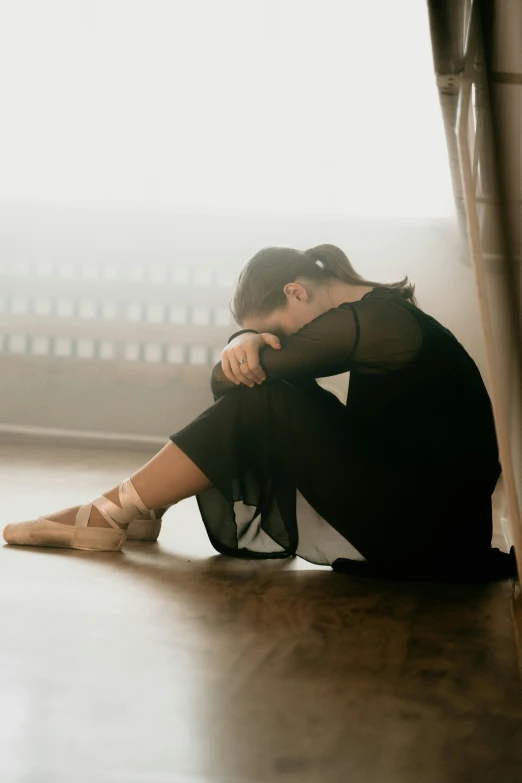 a woman sitting on the floor with her head in her hands, by Elizabeth Polunin, pexels contest winner, prima ballerina, heartbroken, hugging his knees, teenage girl