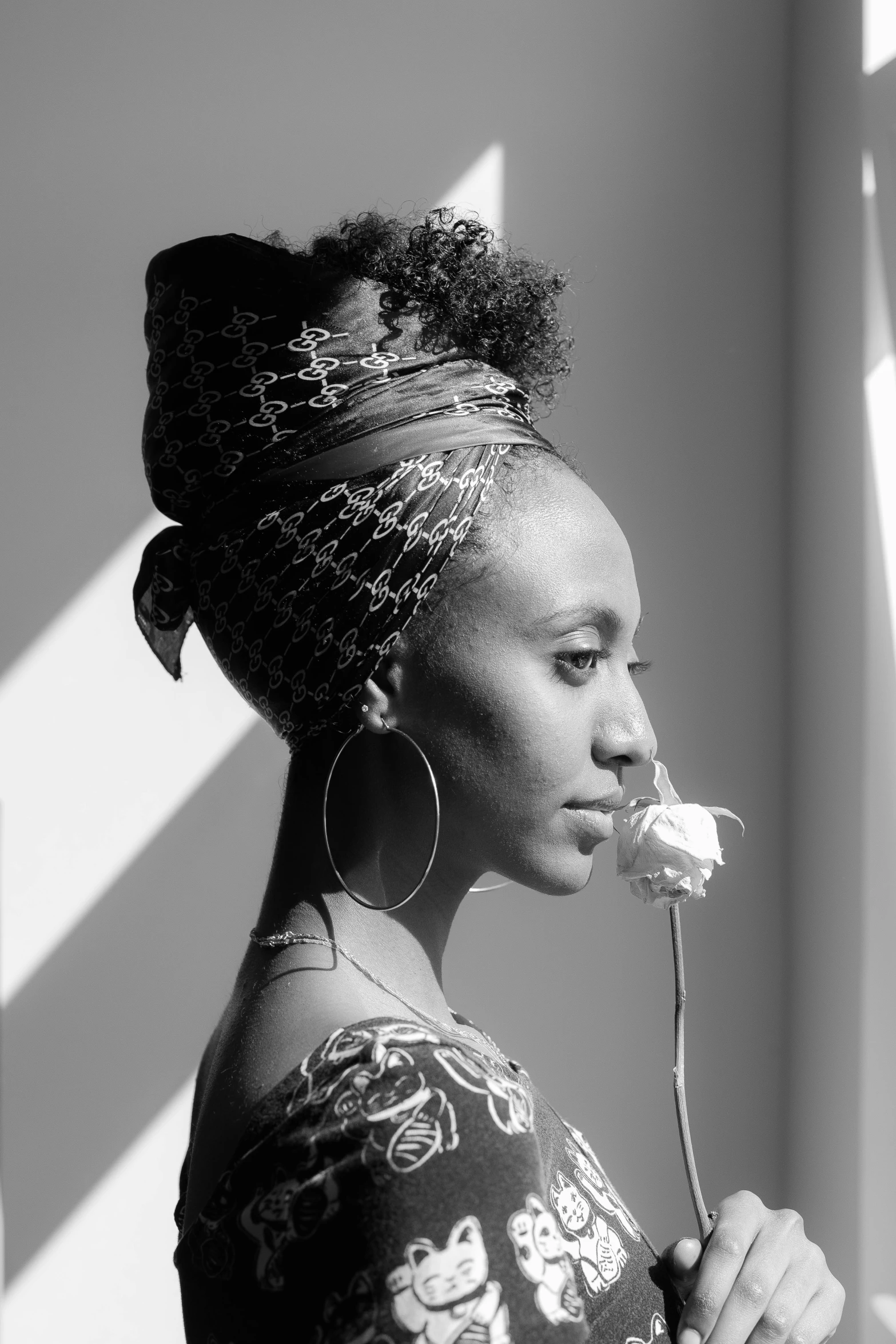 a black and white photo of a woman with a flower in her mouth, inspired by Carrie Mae Weems, pexels contest winner, afrofuturism, square, somali woman, side profile waist up portrait, vibrant light